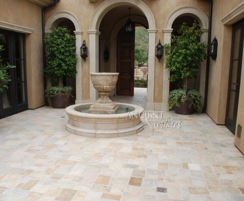 A hand carved entryway courtyard stone fountain sitting on top of reclaimed Arcane Stone flooring. By Ancient Surfaces